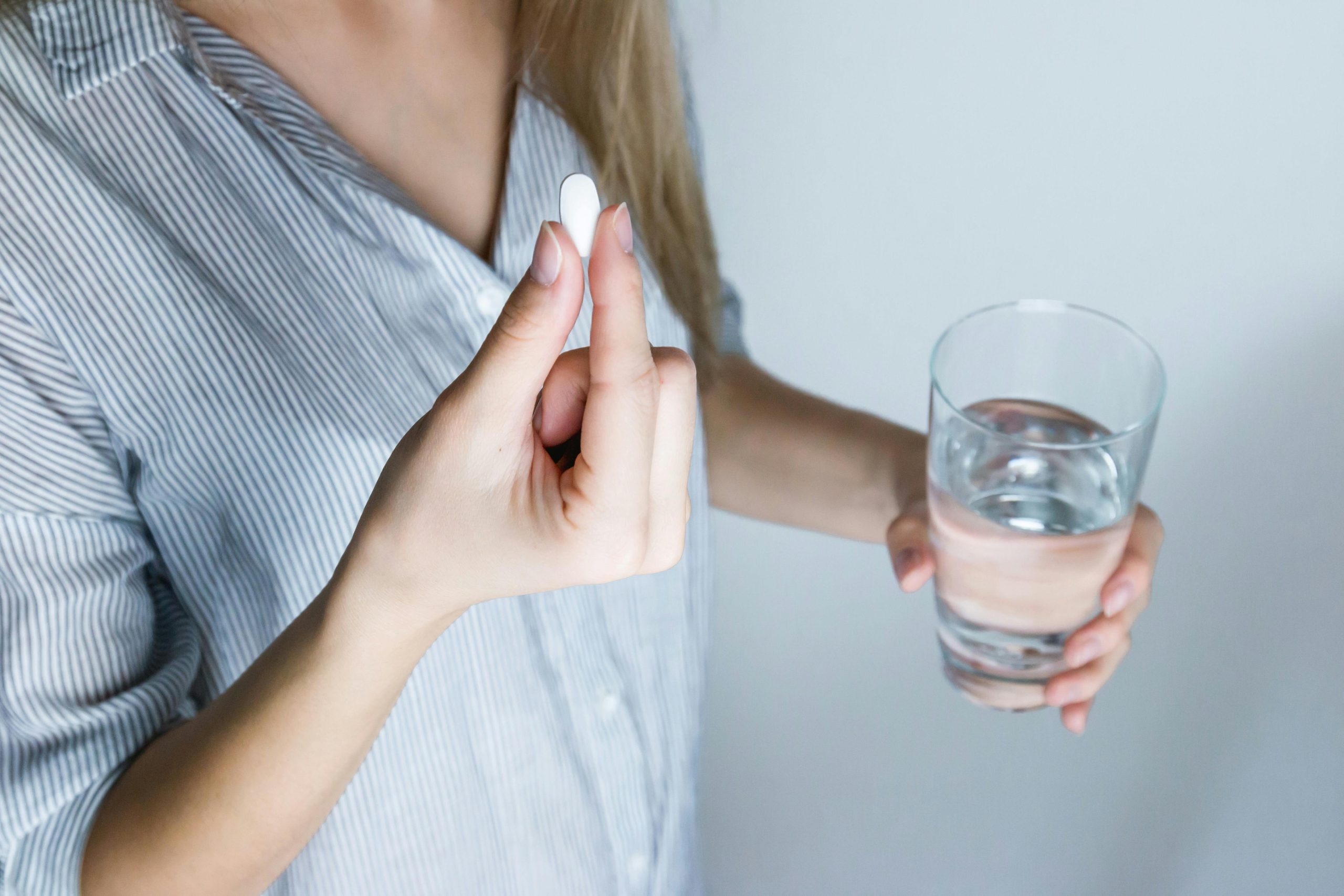 Person holding a pill and glass of water