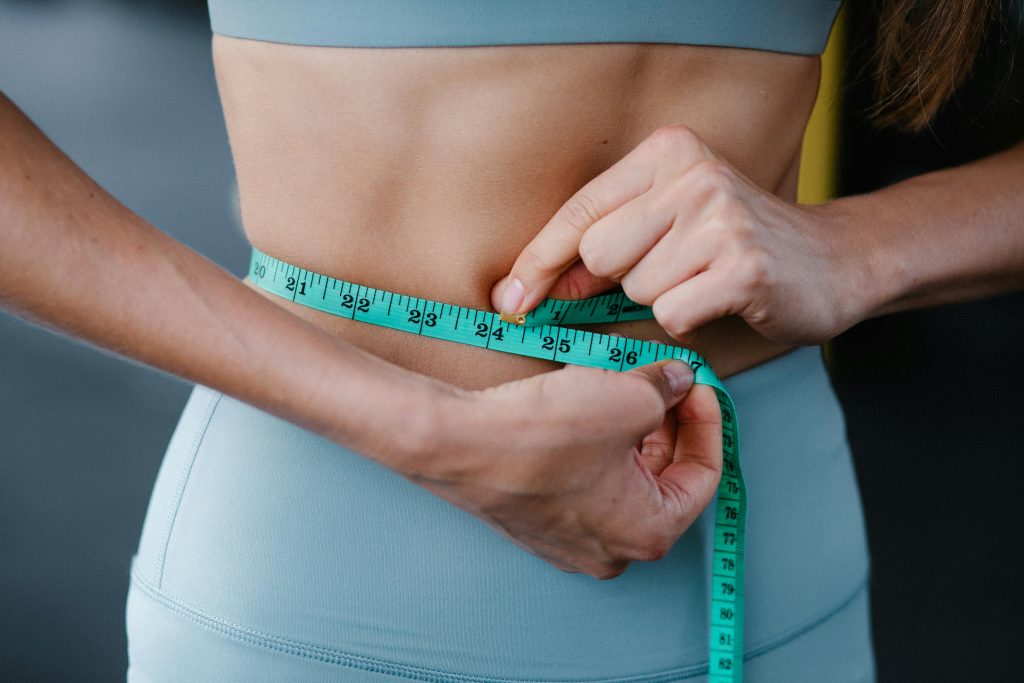 Person measuring waist for weight loss results