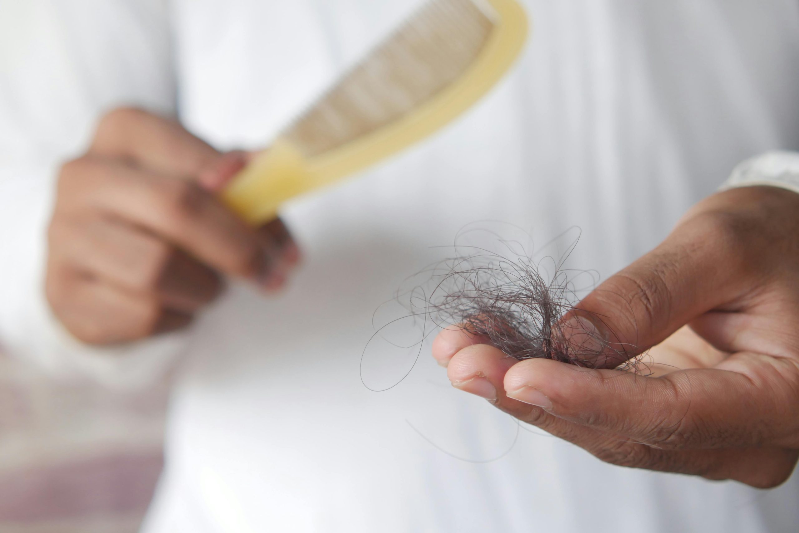 Person holding hair that fell out and a comb