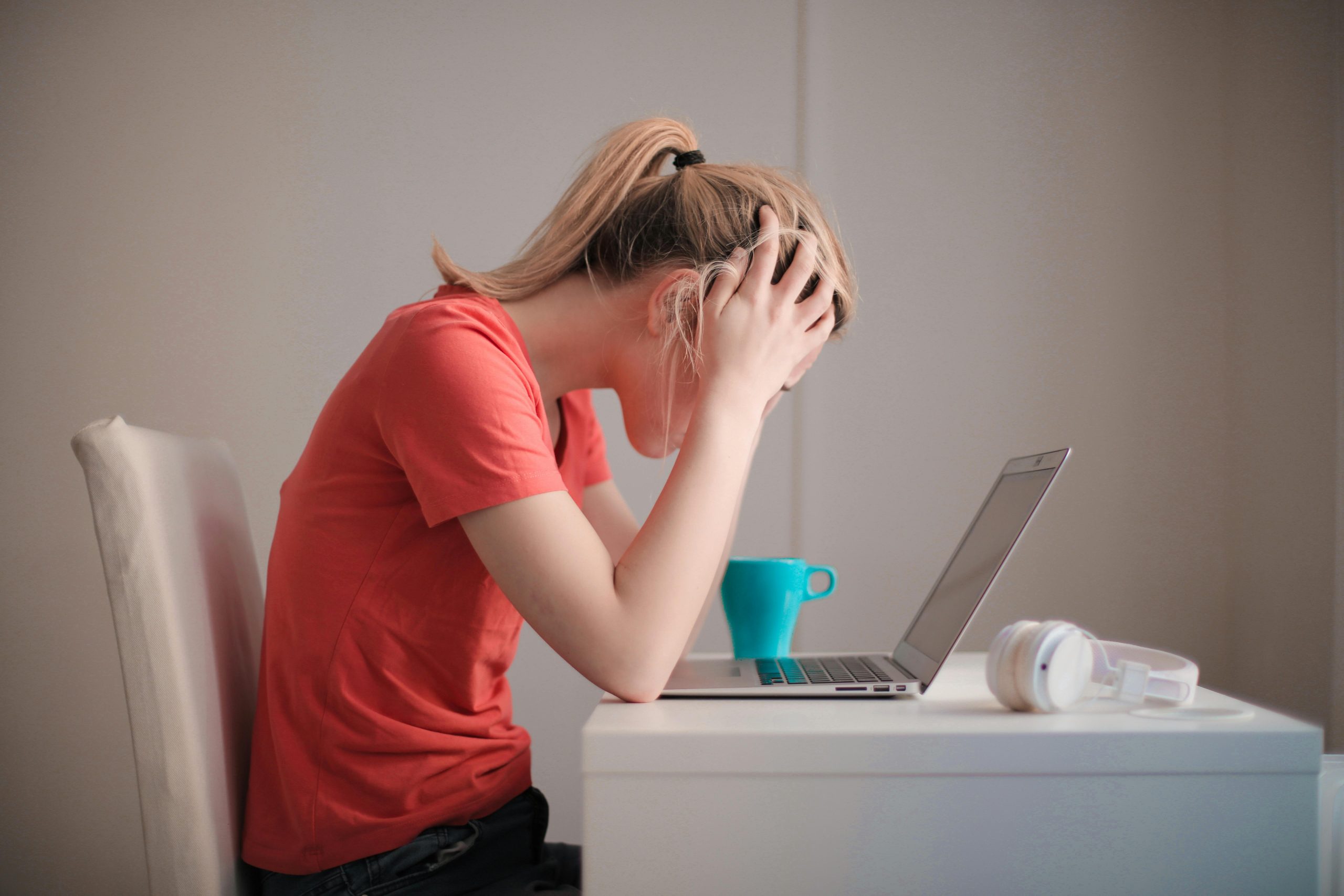 Woman sitting at a desk holding her head having anxiety